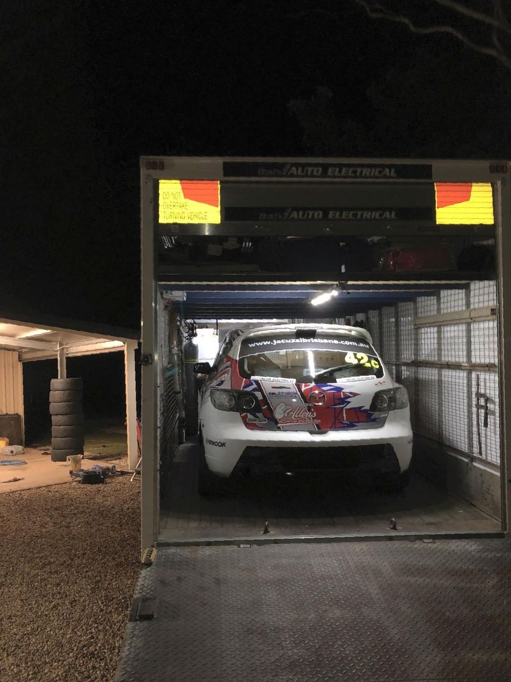 A Race Car Is Being Loaded Into A Trailer At Night — Brad's Auto Electrical in Mareeba, QLD
