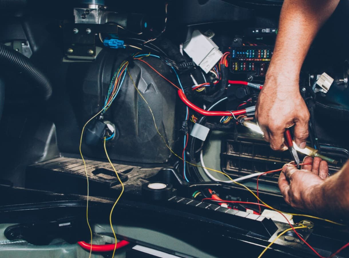 A Man Is Working On The Wiring Of A Car — Brad's Auto Electrical in Mareeba, QLD