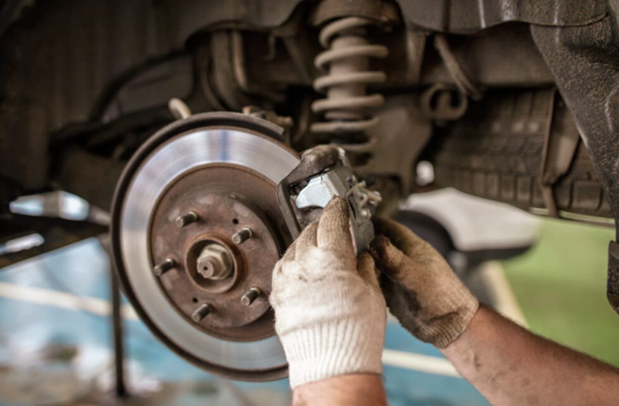 A Person Is Fixing The Brake Pads On A Car — Brad's Auto Electrical in Mareeba, QLD