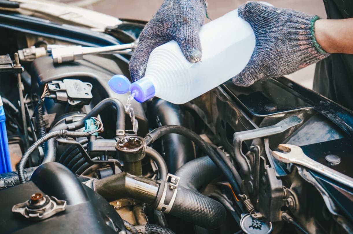 A Person Is Pouring Water Into A Car Radiator — Brad's Auto Electrical in Mareeba, QLD