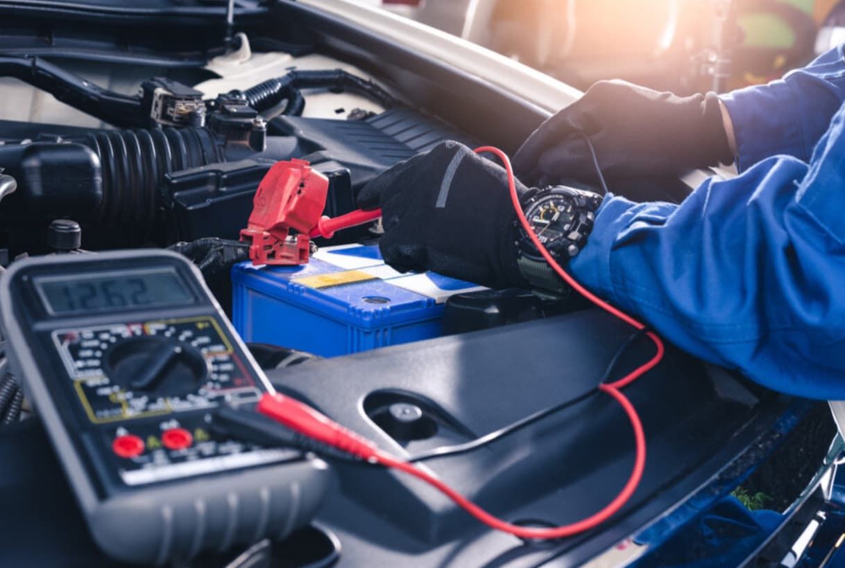 A Mechanic Is Working On A Car Battery With A Multimeter — Brad's Auto Electrical in Mareeba, QLD