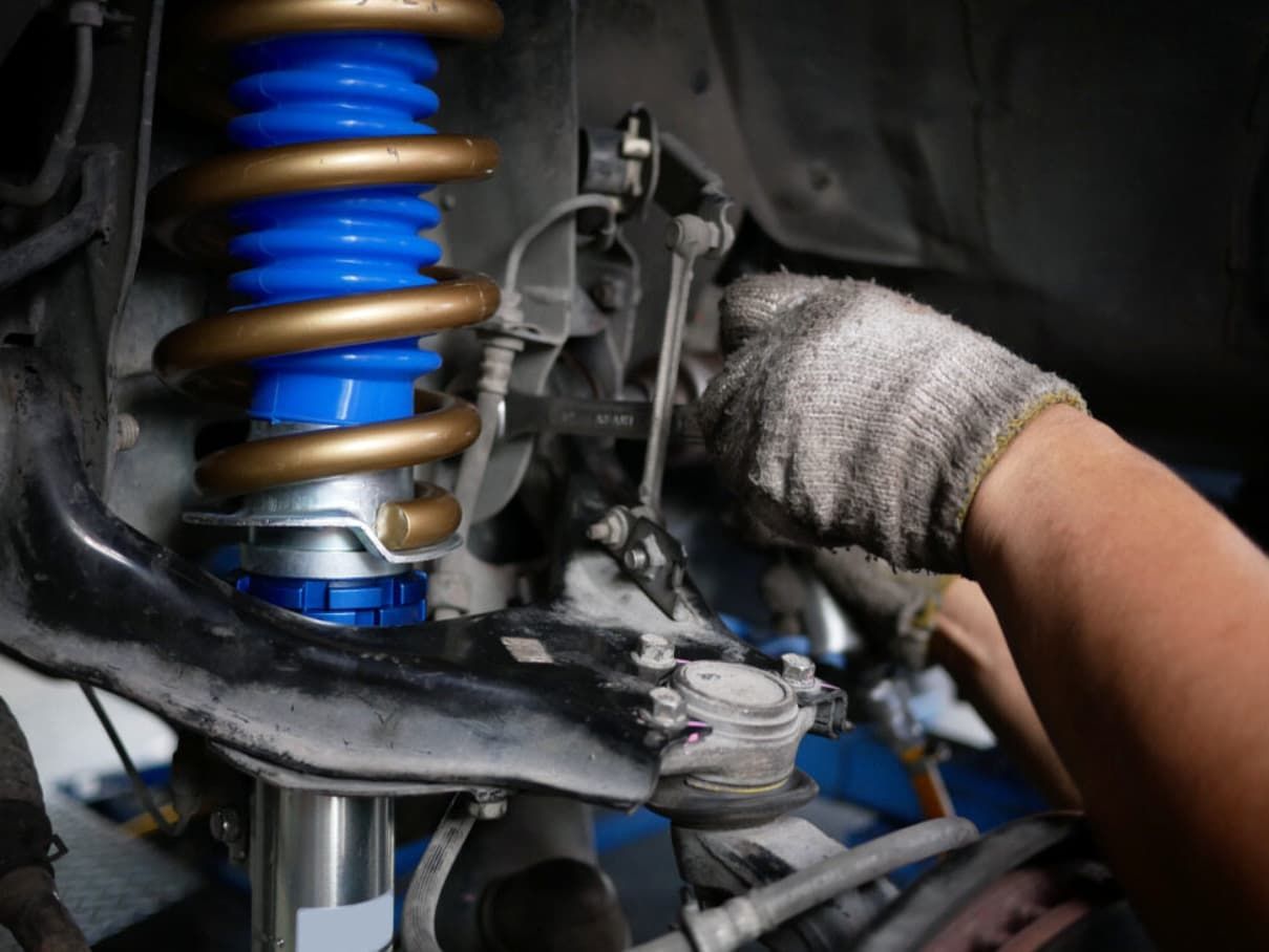 A Person Is Working On A Car Suspension With A Wrench — Brad's Auto Electrical in Mareeba, QLD
