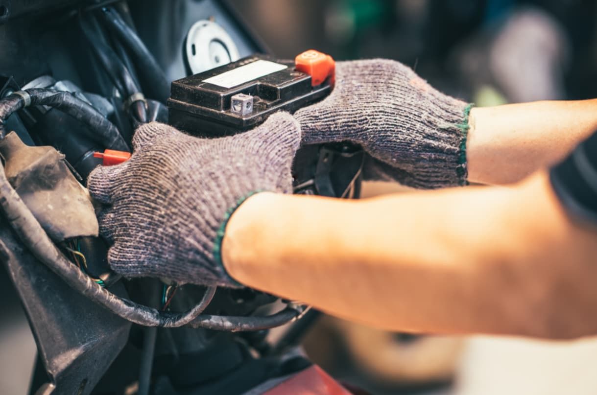 A Person Is Holding A Motorcycle Battery In Their Hands — Brad's Auto Electrical in Mareeba, QLD
