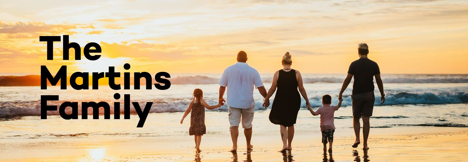 A family is walking on the beach holding hands.