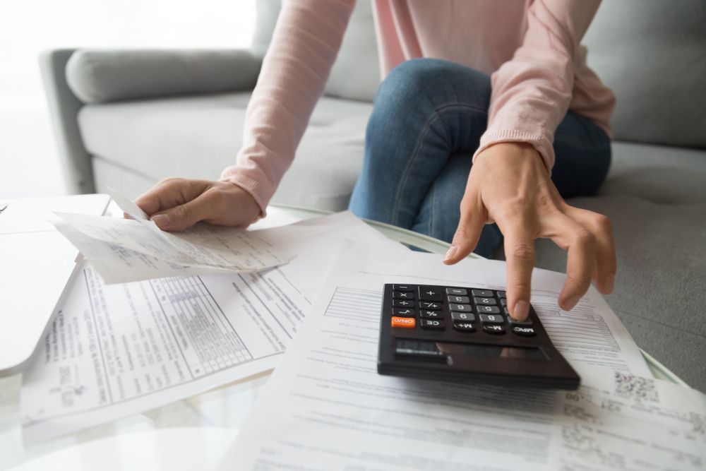 Woman Using a Calculator, Surrounded by Bills — Careful Books in Tablelands, QLD