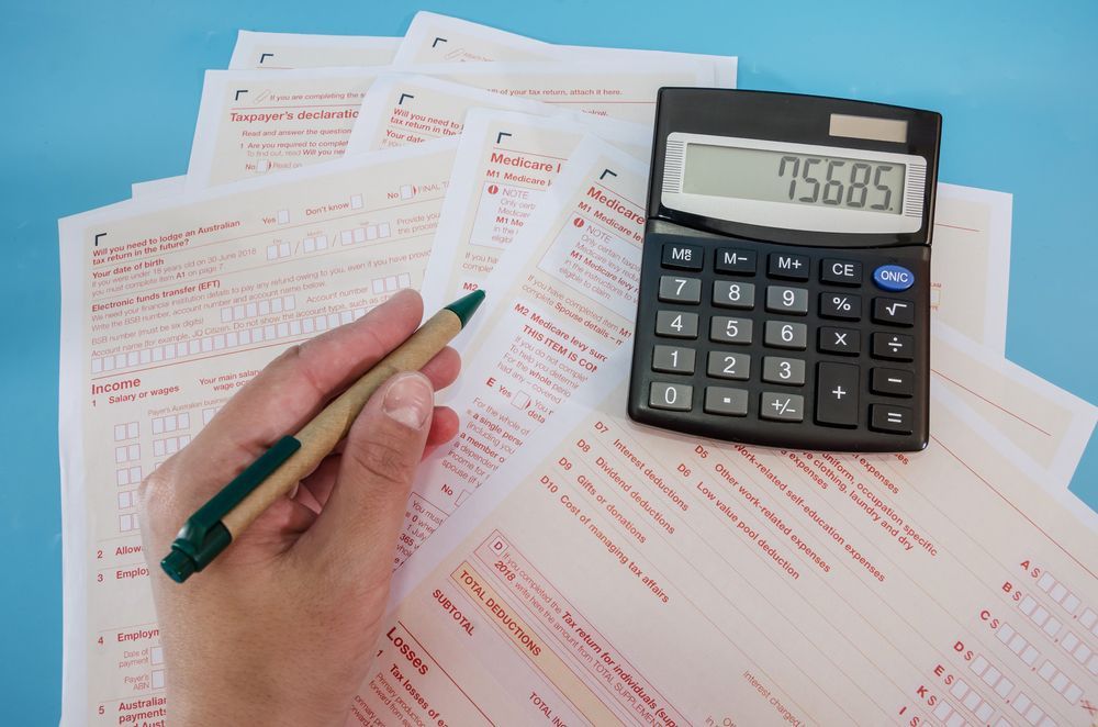 Hand Holding Pen Over Forms With a Calculator — Careful Books in Torres Strait, QLD