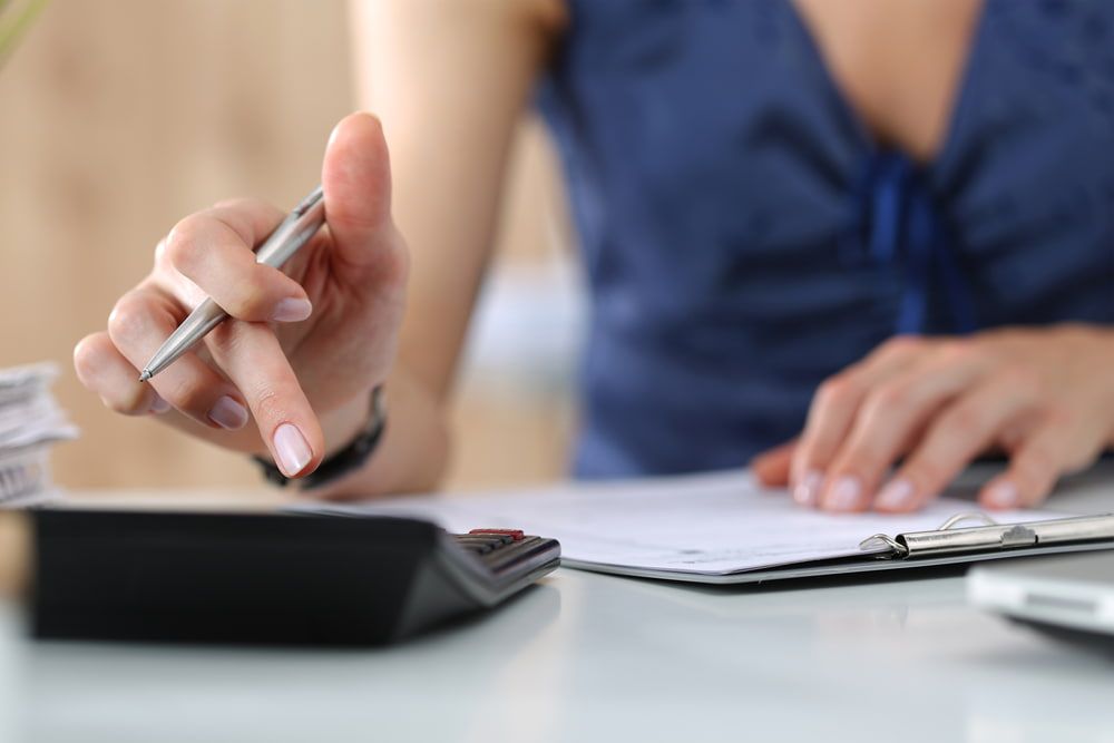 Woman's Hand Pointing at Calculator Holding Pen — Careful Books in Westcourt, QLD