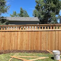 A wooden fence is being built in the backyard of a house.