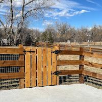 A wooden fence with a gate in the middle of a field.