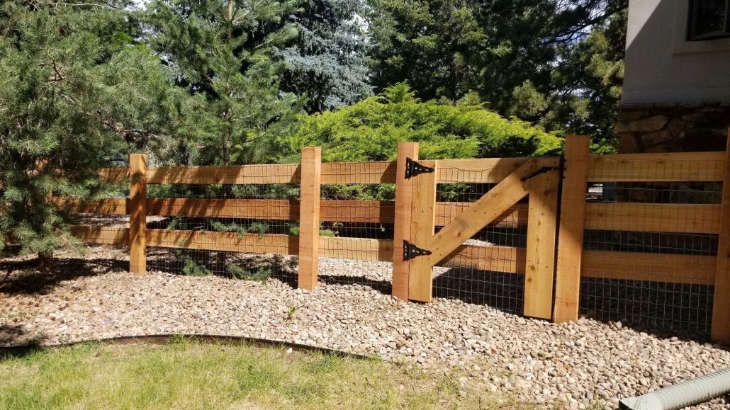 A wooden fence with a gate in front of a house.
