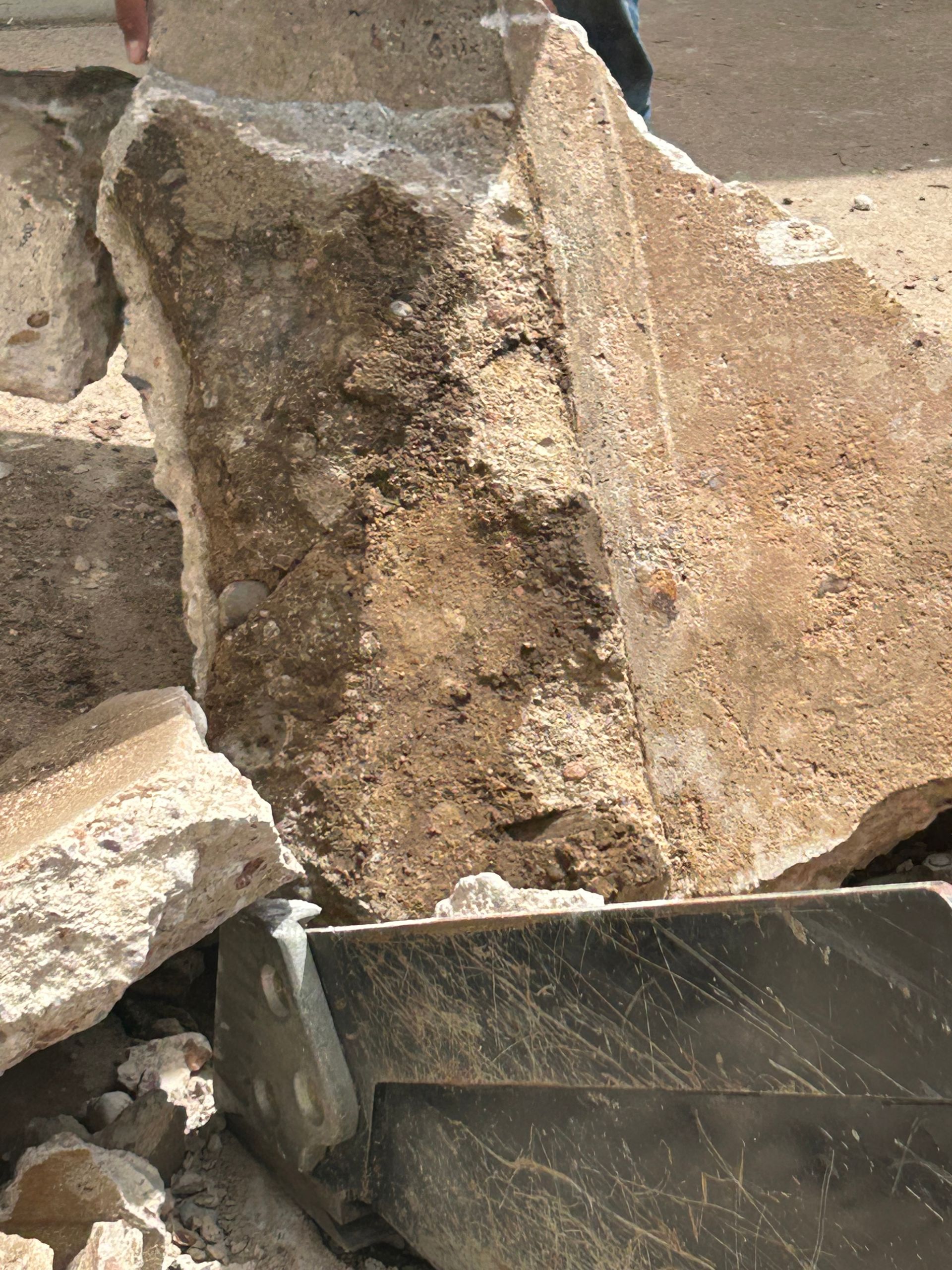 Close-up of broken concrete and stone rubble beside a metal container