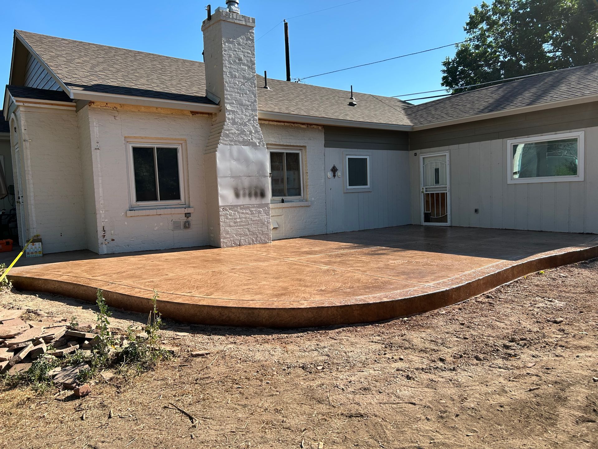 Backyard with a newly built raised wooden deck beside a stucco house and chimney