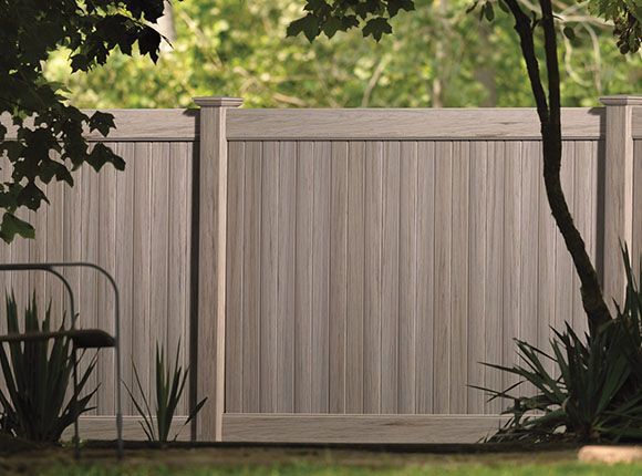 A black fence with a door in the backyard of a house.