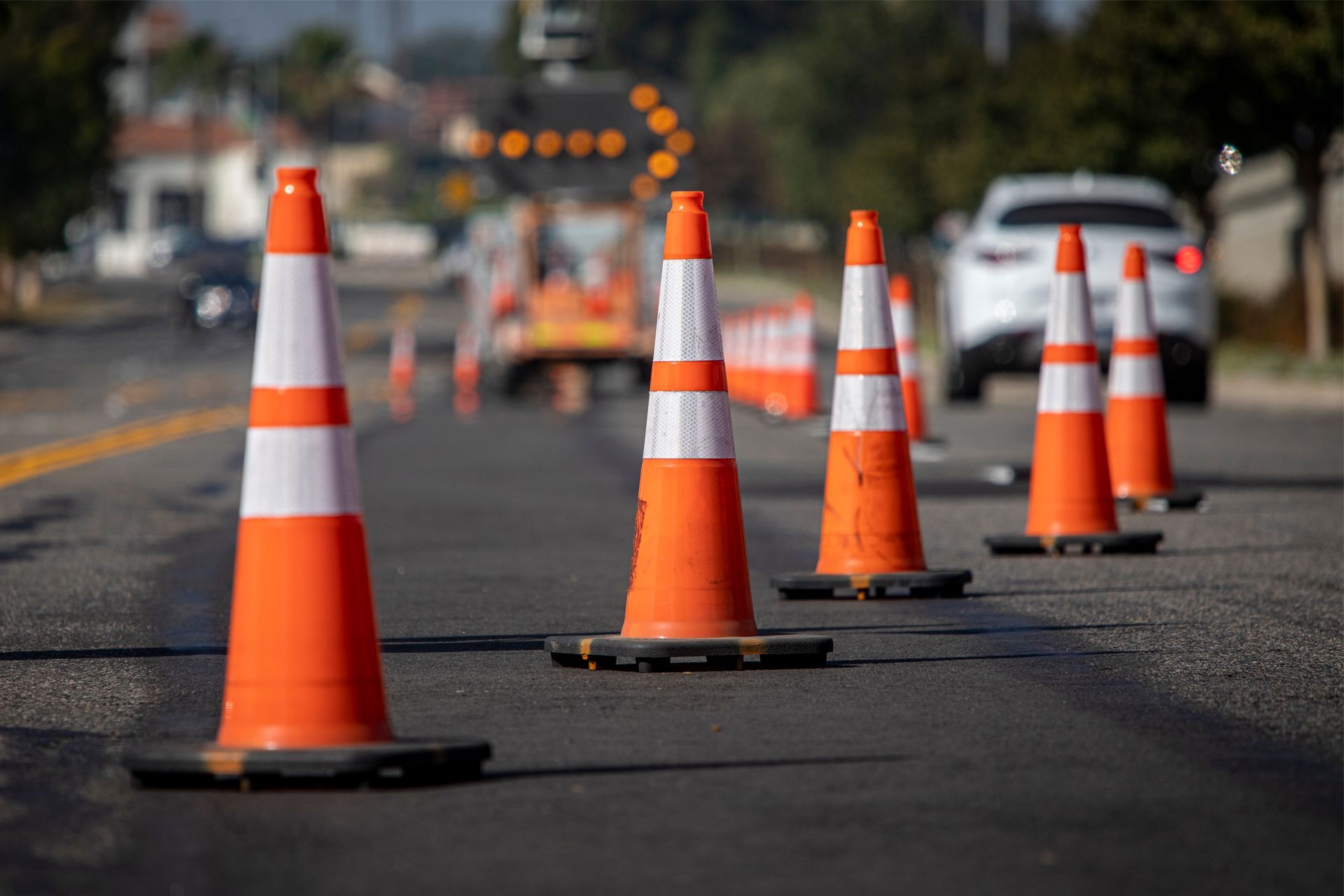 A row of orange and white traffic cones on the side of a road