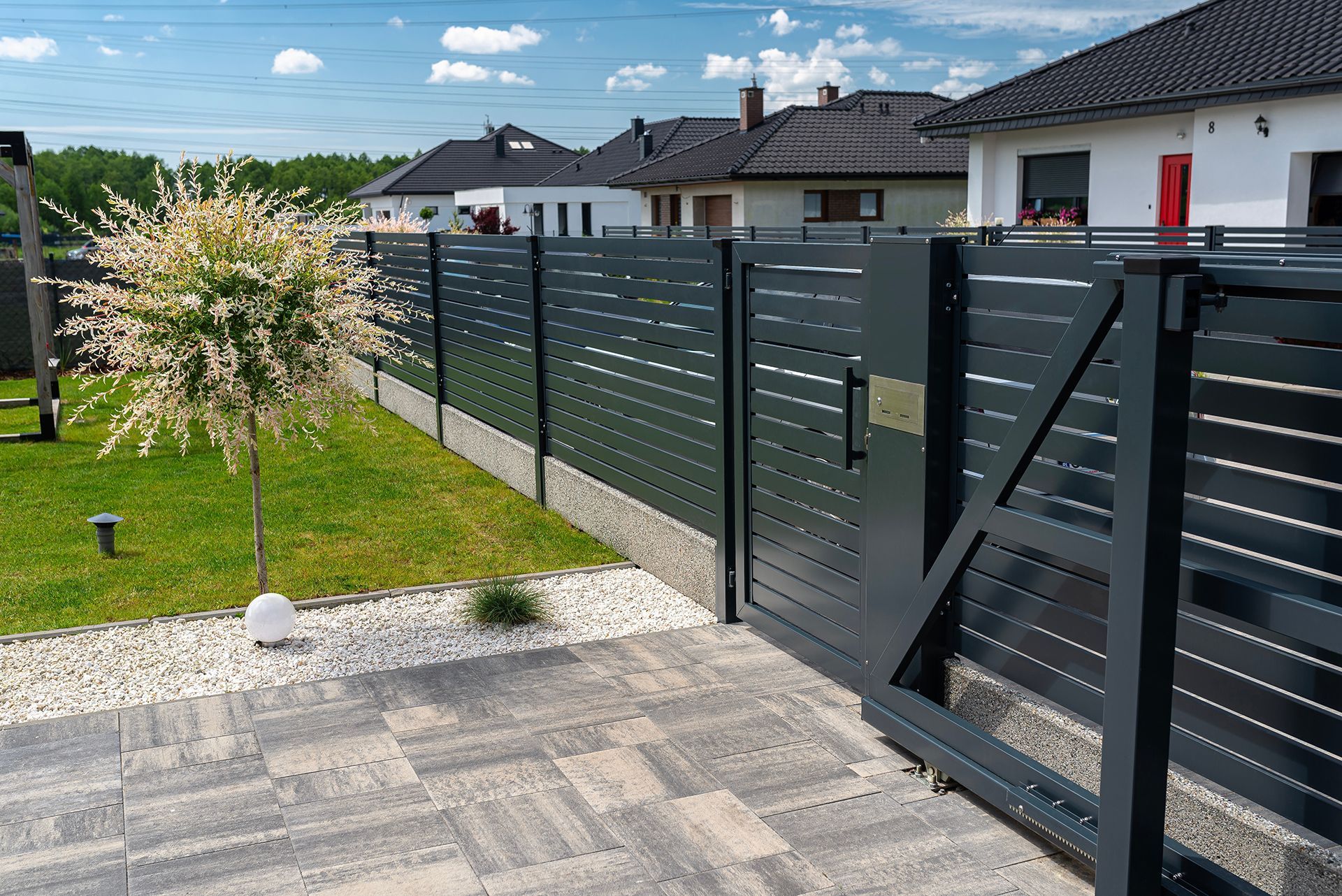 A black fence with a sliding gate in front of a house.