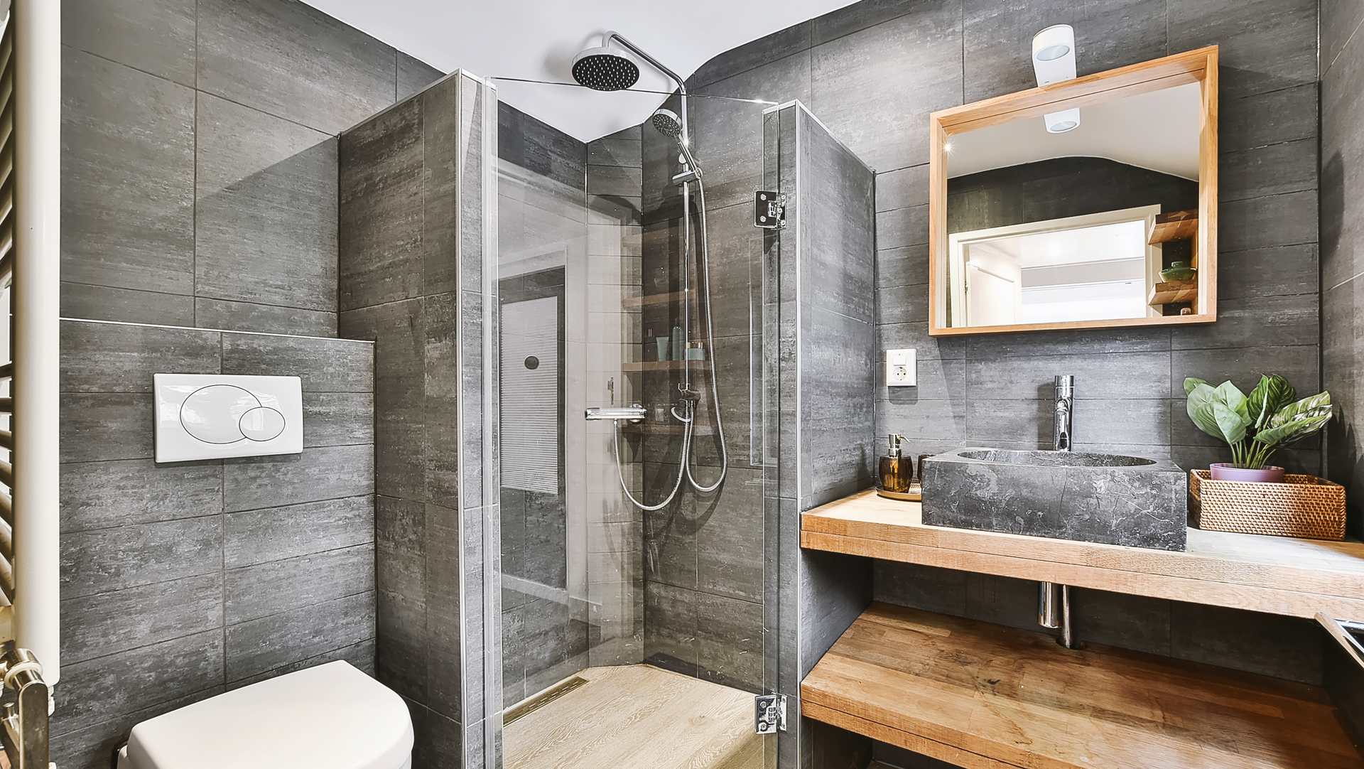 A bathroom with a toilet , sink , mirror and walk in shower.