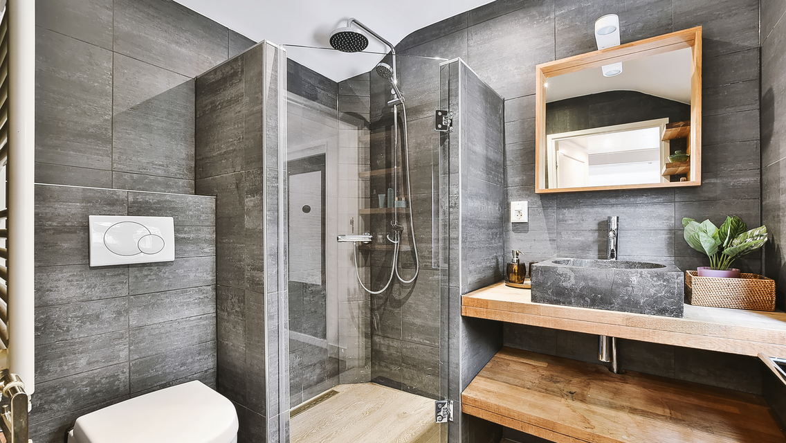 A bathroom with a toilet , sink , mirror and walk in shower.
