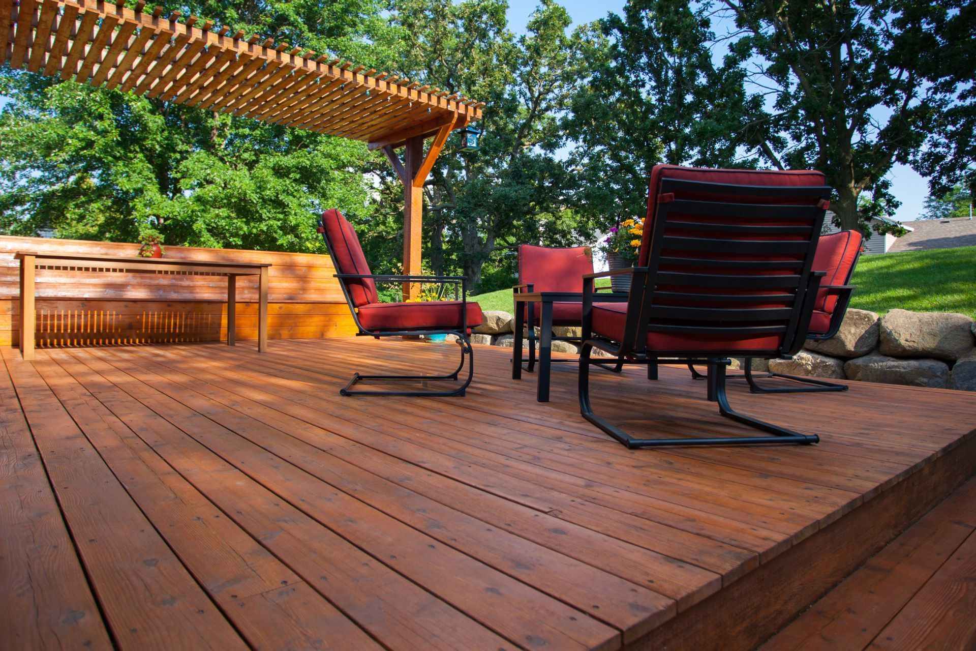 A wooden deck with chairs and a table under a pergola.