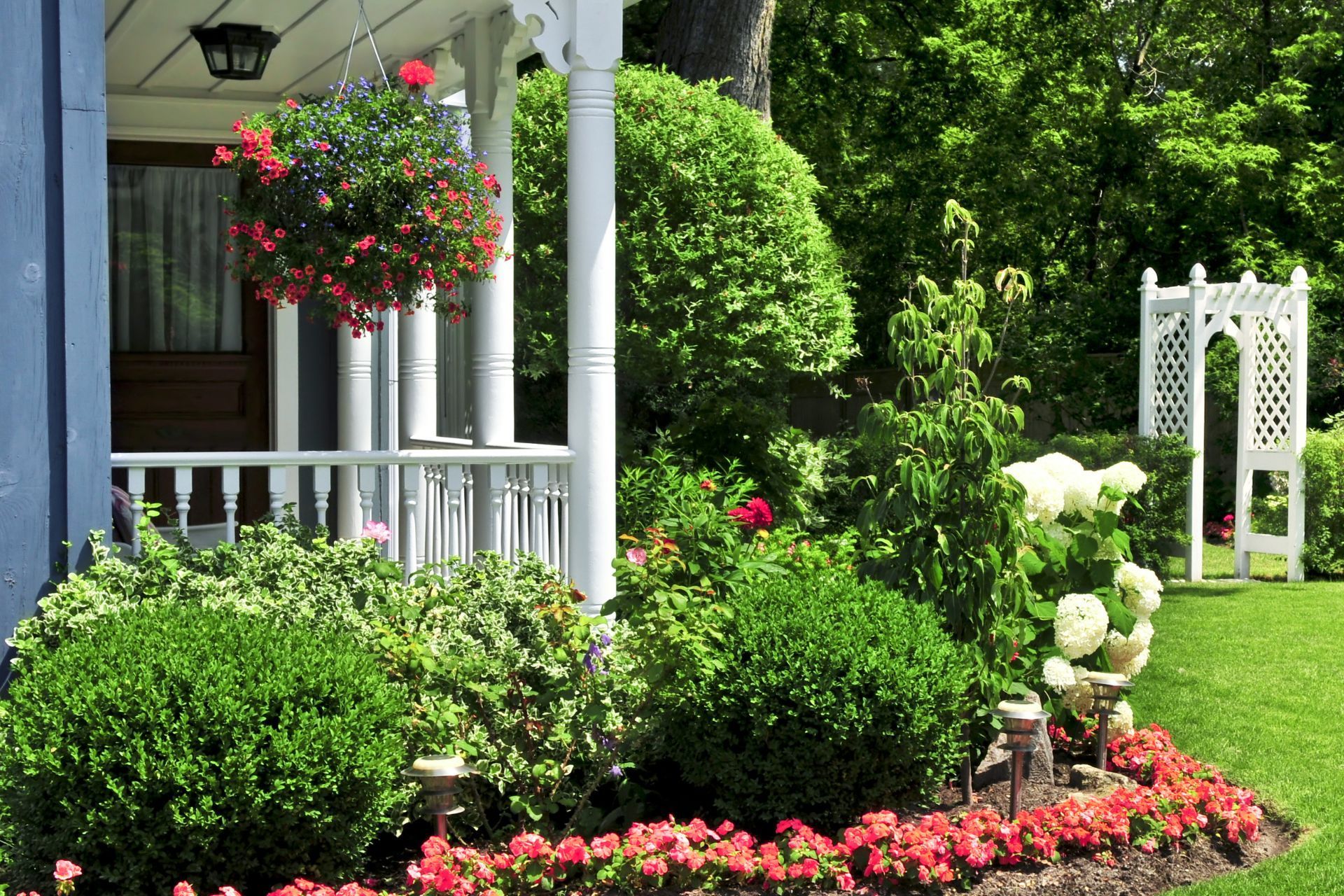 A white porch with hanging baskets of flowers on it