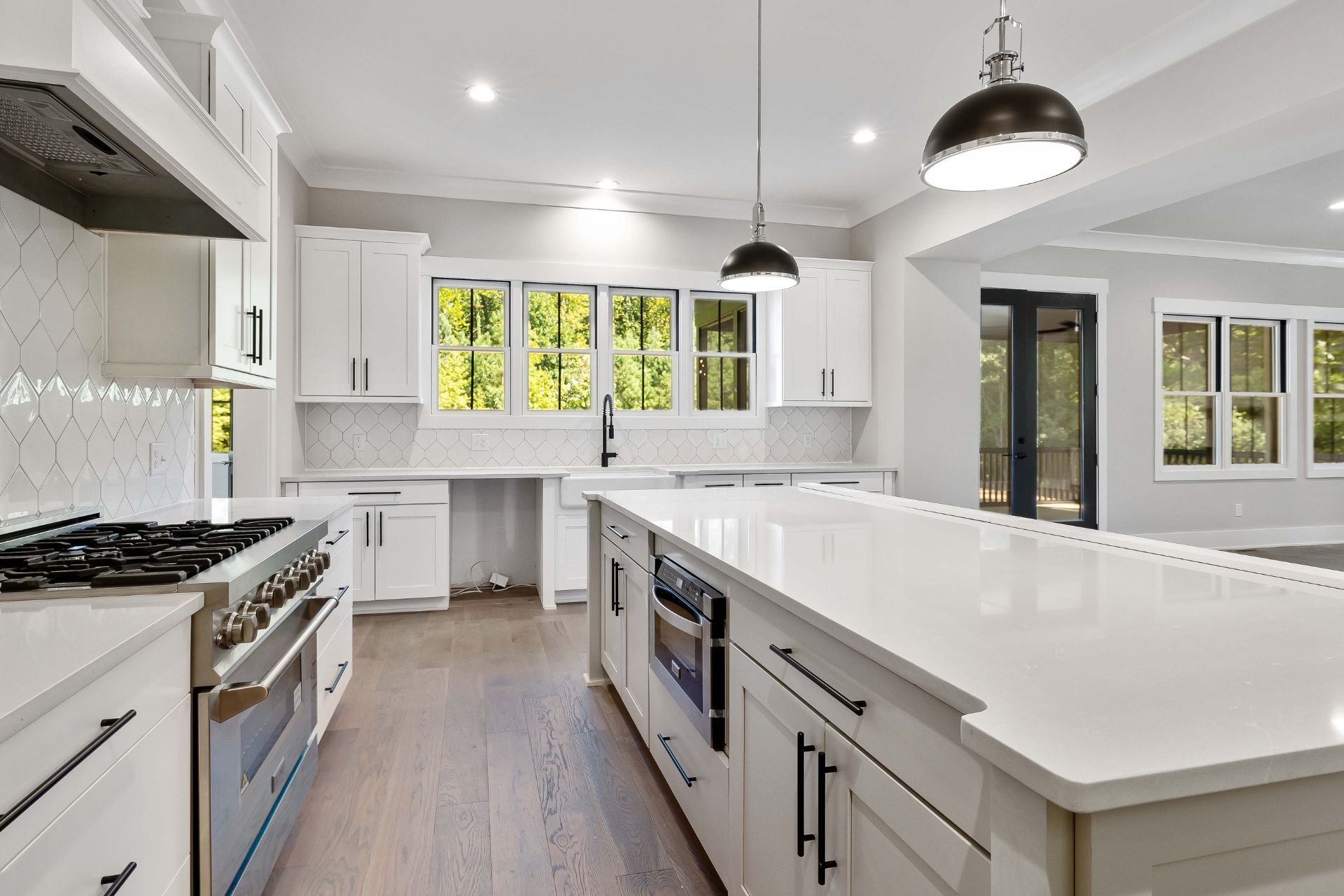 A kitchen with white cabinets , stainless steel appliances , and a large island.