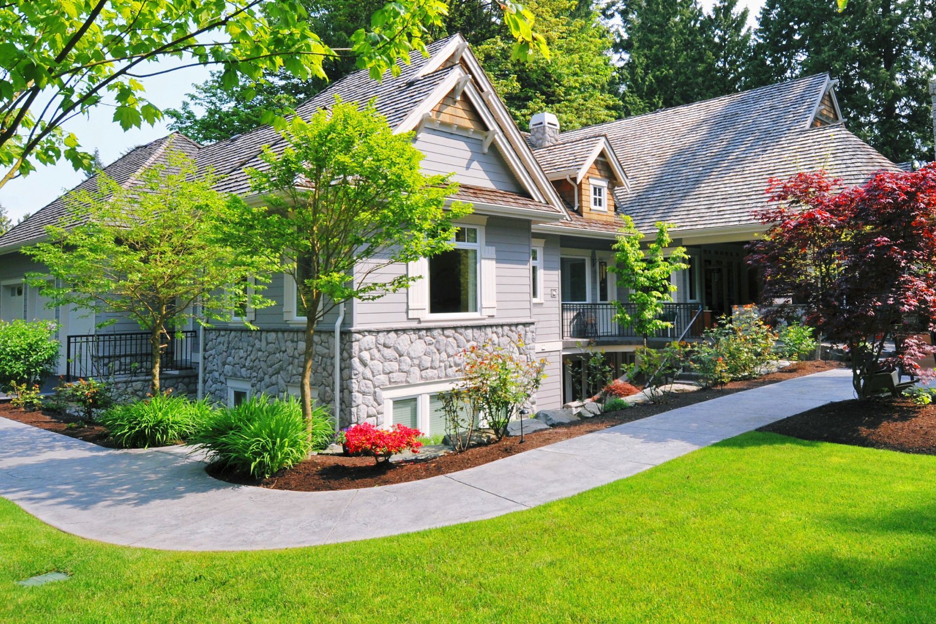 A large house with a lush green lawn and trees in front of it