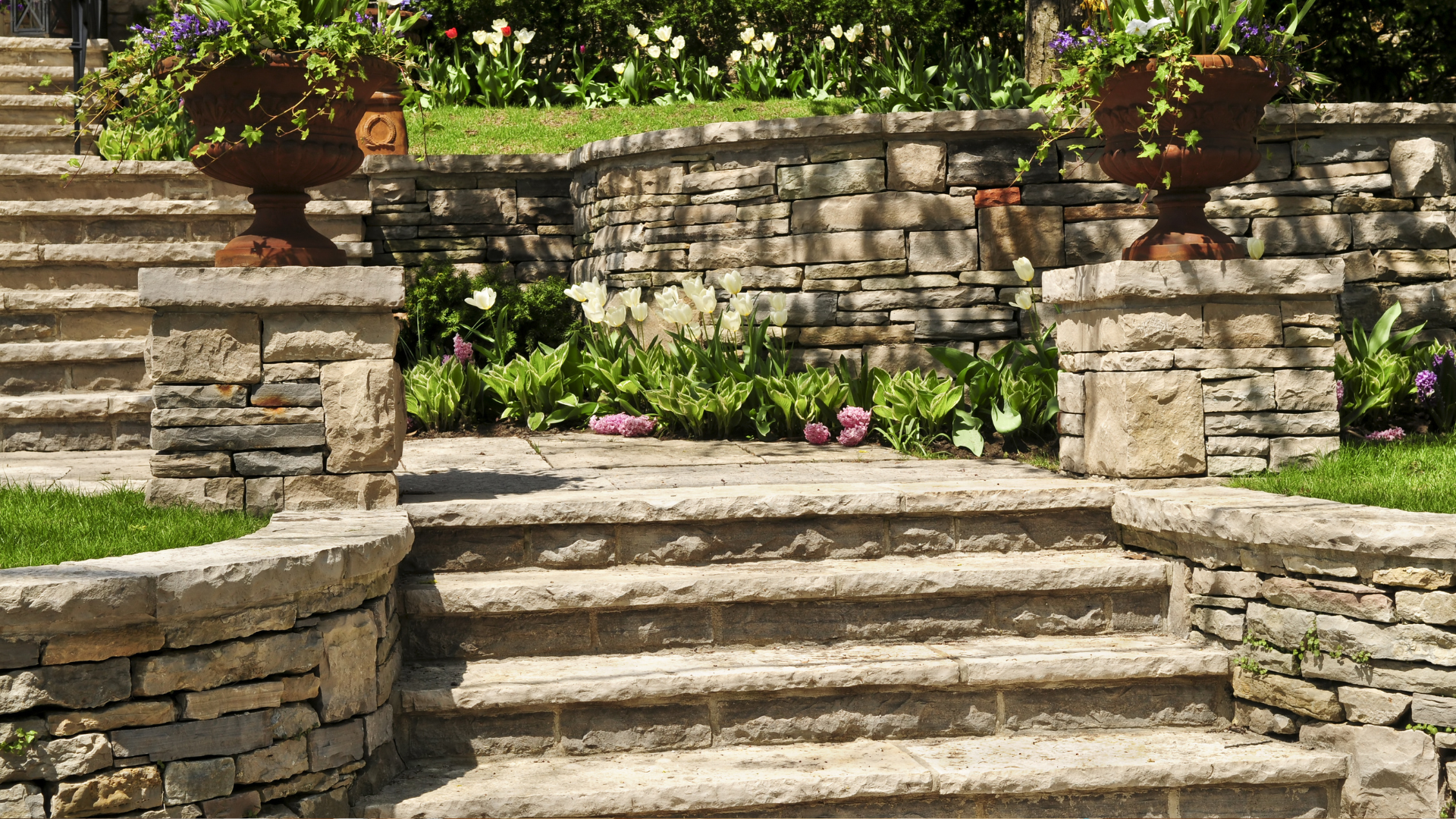 A set of stone stairs leading up to a stone wall in a garden.