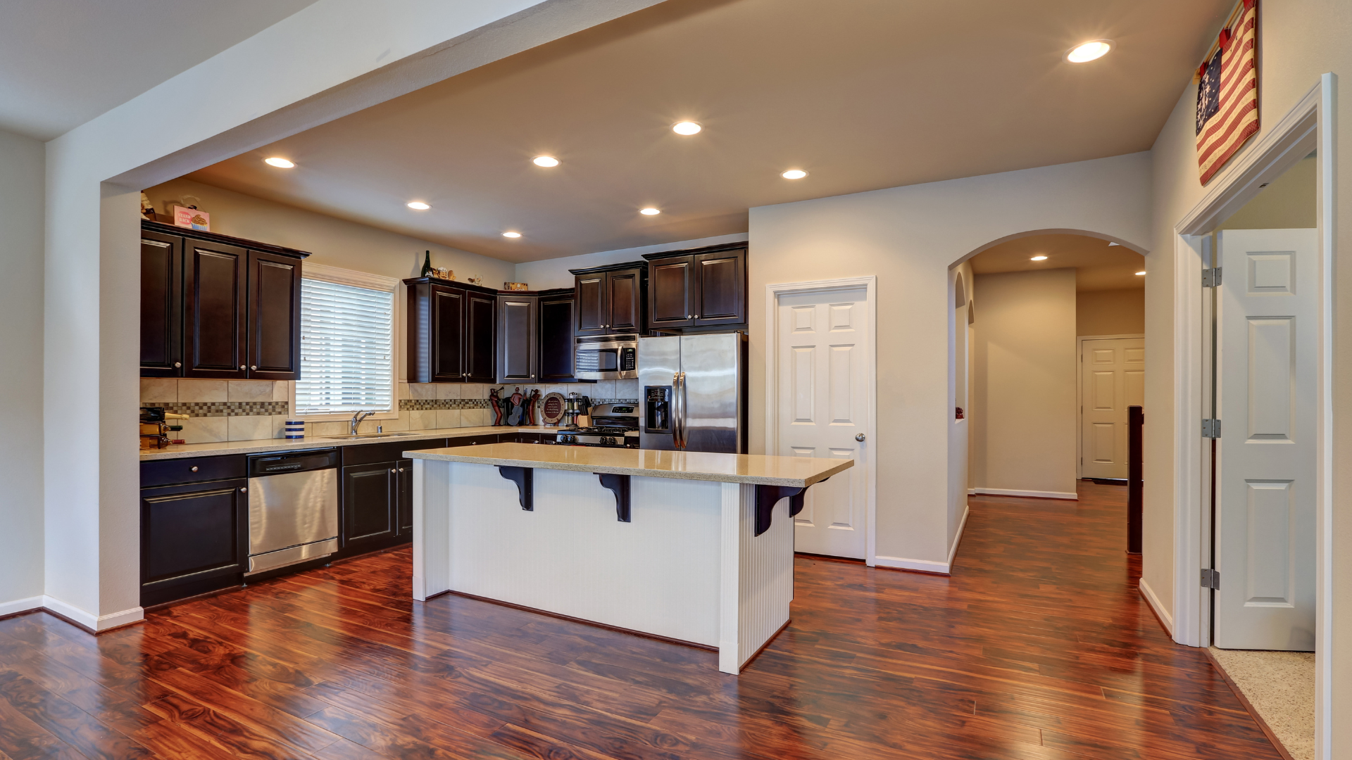 A kitchen with a large island in the middle of it and hardwood floors.