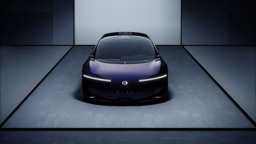 Sleek black sports car centered in a dark showroom, lit by soft overhead light.