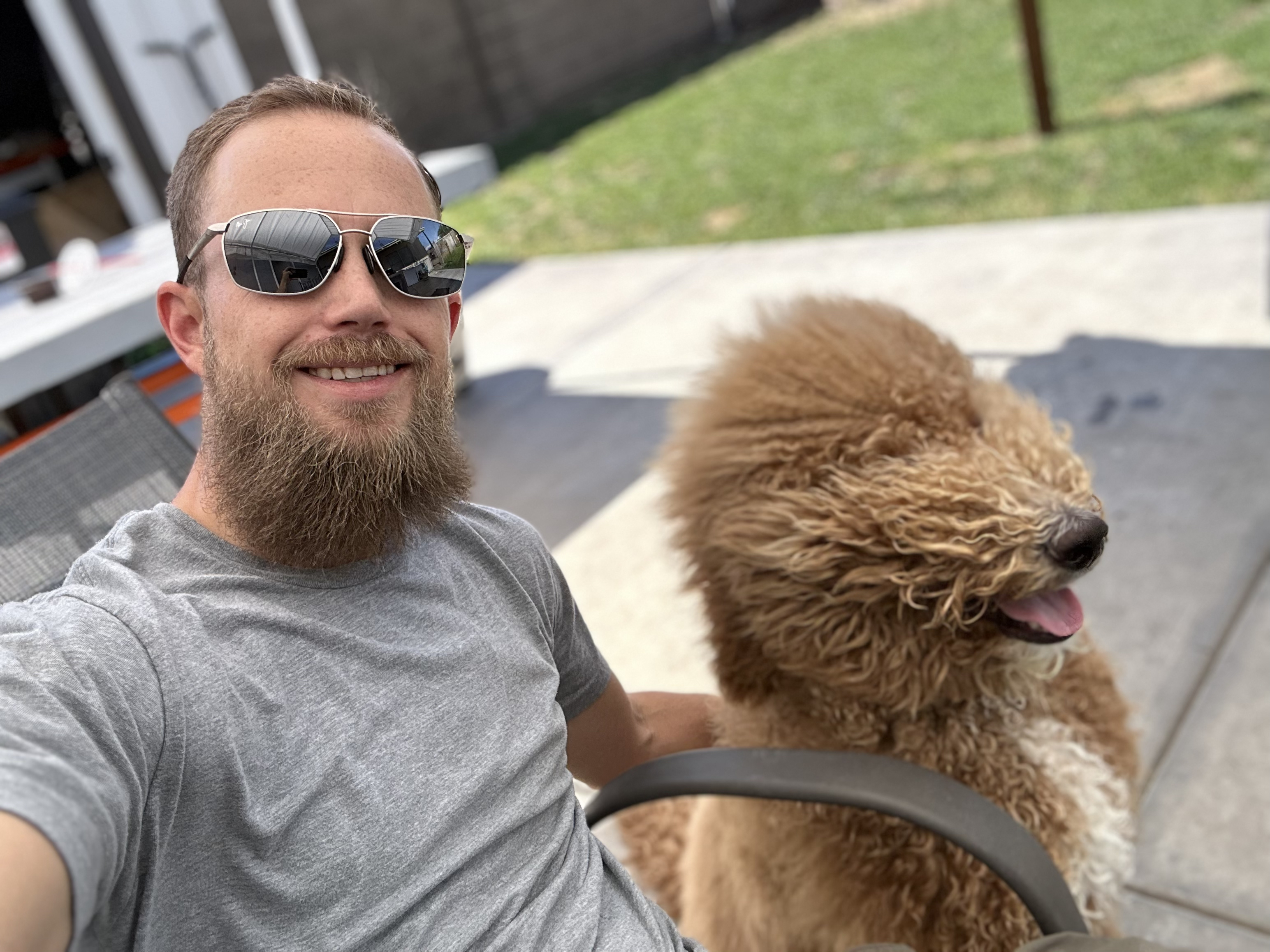 A man with a beard is taking a selfie with his dog.