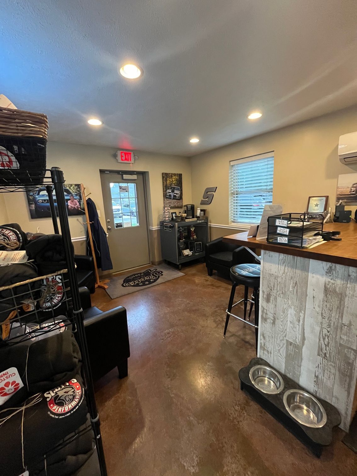Interior shop view with items for sale, a desk, exit door, and dog bowls. | Scott's Garage