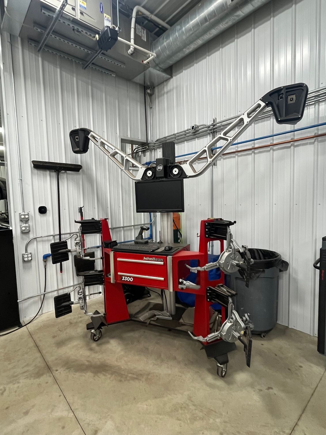 Wheel alignment machine in a garage. Red tool chest, white walls, and silver arm with sensors. | Scott's Garage