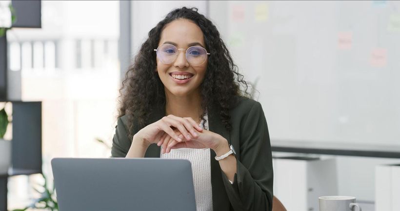 A woman is sitting at a desk in front of a laptop computer.