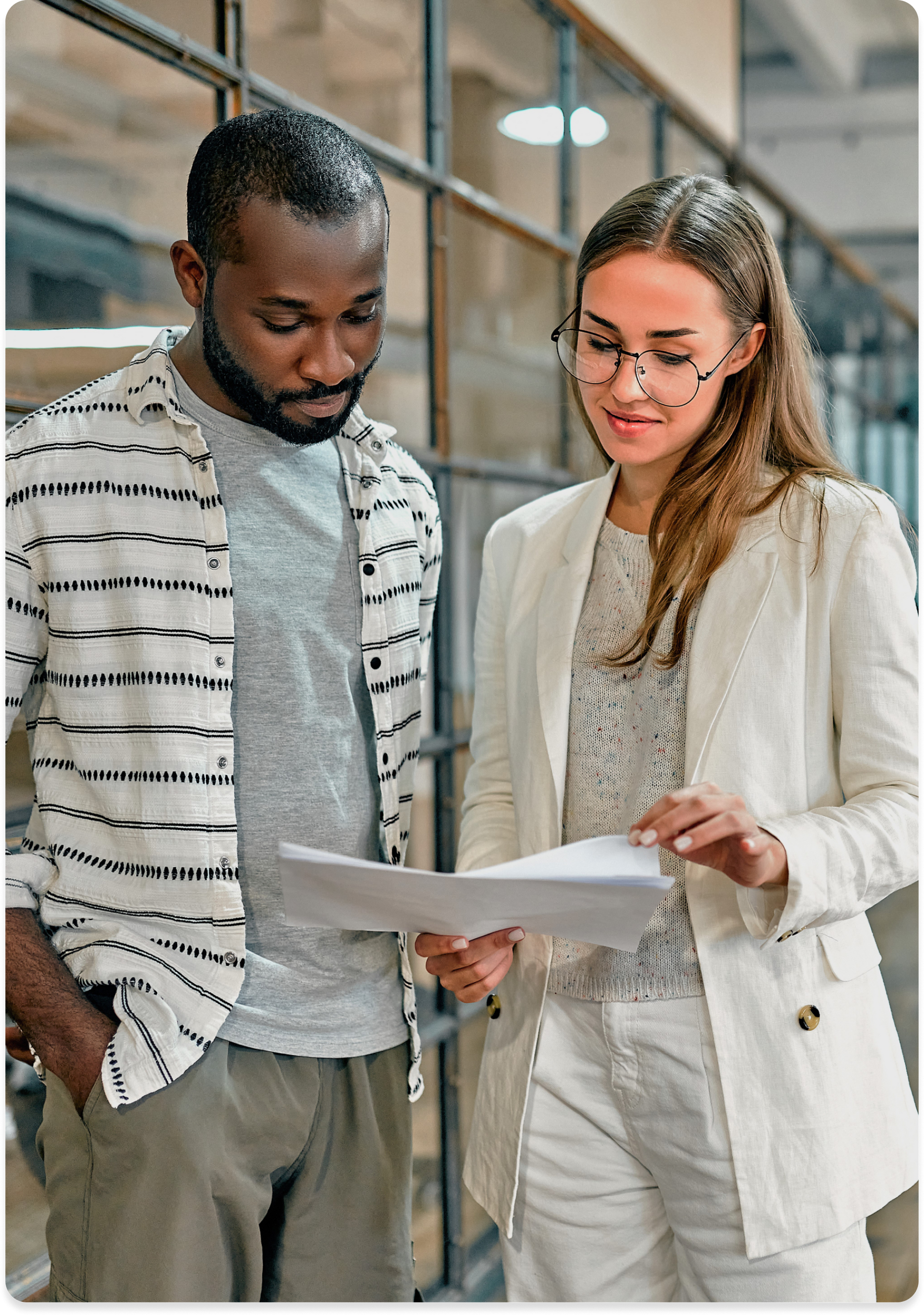 Two colleagues reviewing papers in an office corridor.