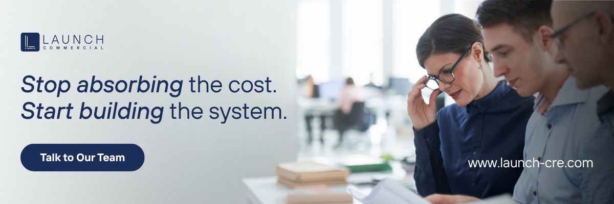 Two businesspeople reviewing a laptop and tablet beside text: “Stop absorbing the cost. Start building the system.”
