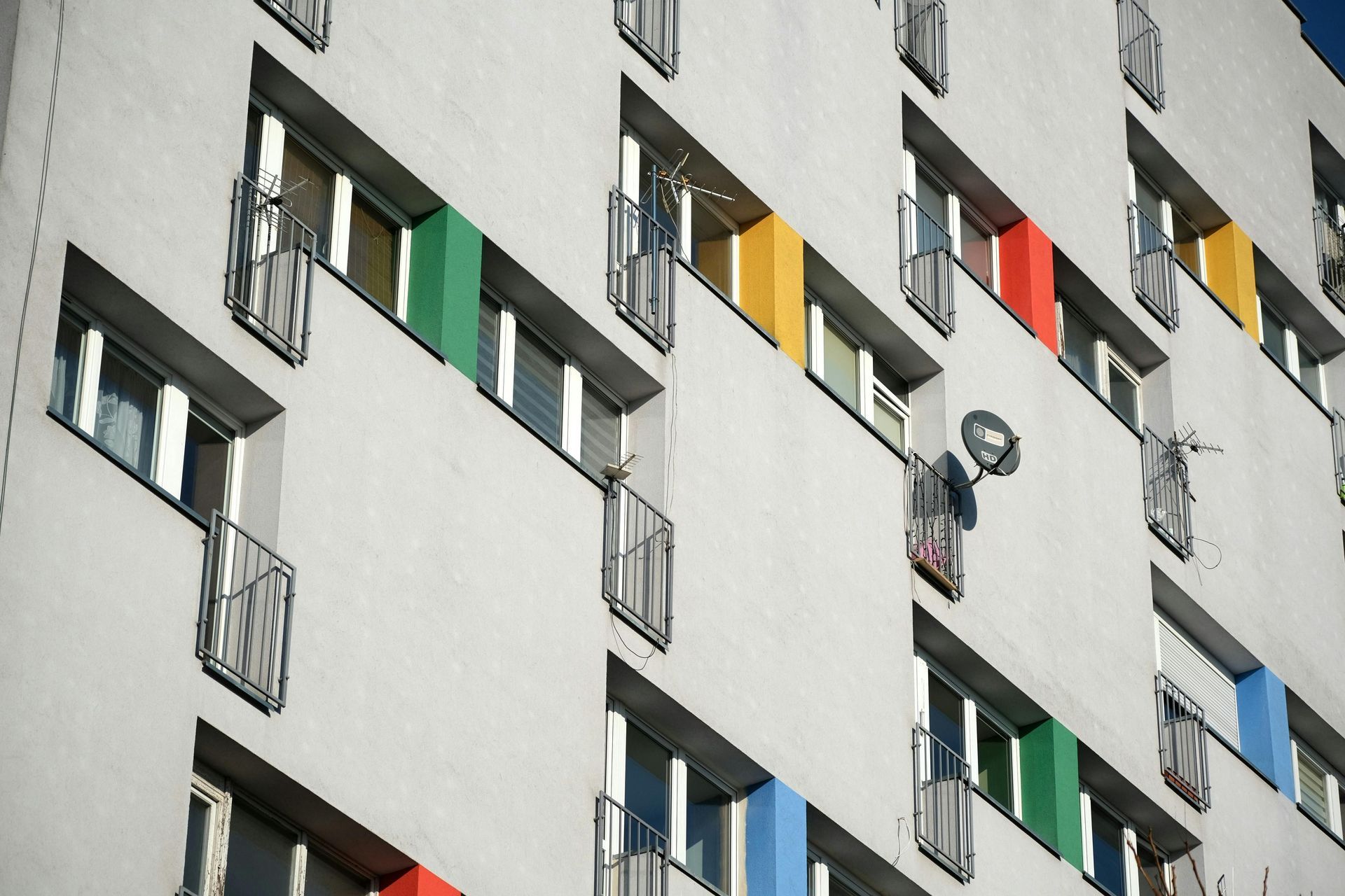 Apartment building facade with rows of open windows and colorful curtains