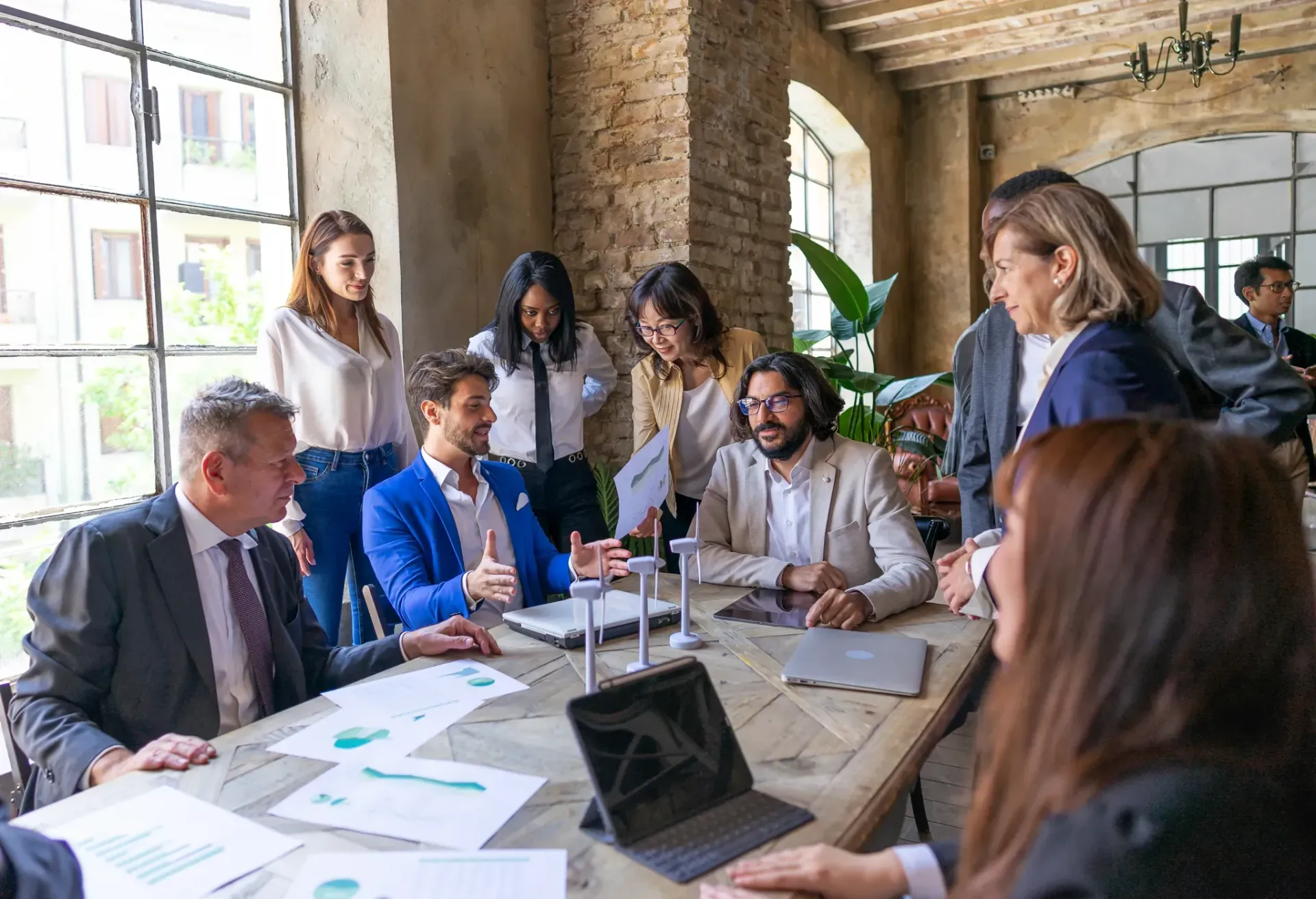 Group of people in business attire at a table, discussing documents in a modern office.