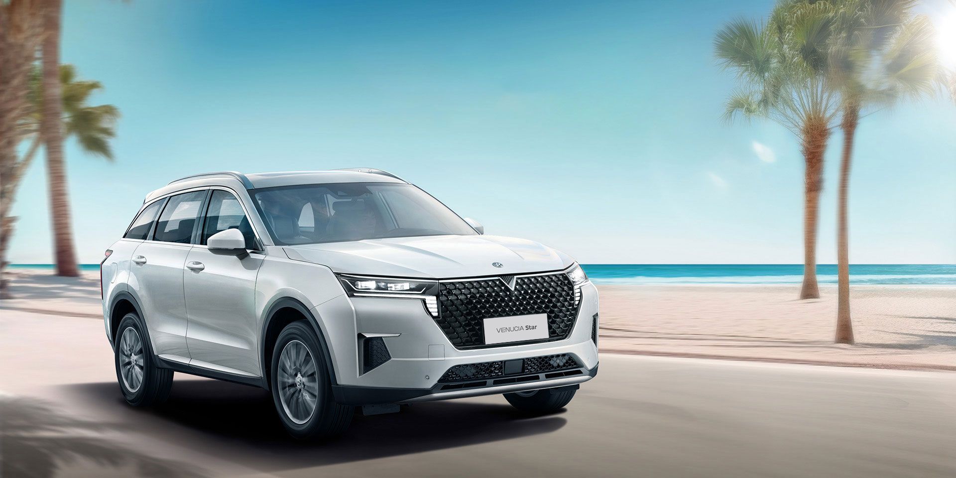 White SUV driving on road near beach with palm trees and ocean.