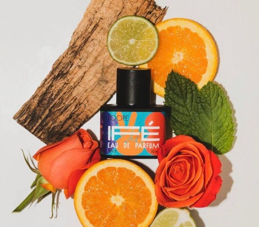 A bottle of ife eau de parfum surrounded by fruits and flowers