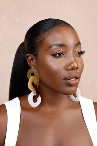 A close up of a woman wearing earrings and a ponytail.