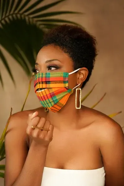A woman wearing a colorful face mask and earrings.