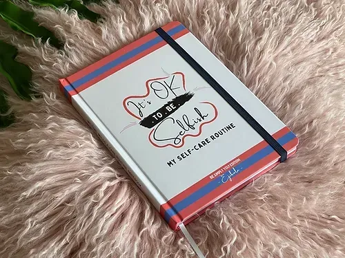 A notebook is sitting on top of a fluffy blanket.
