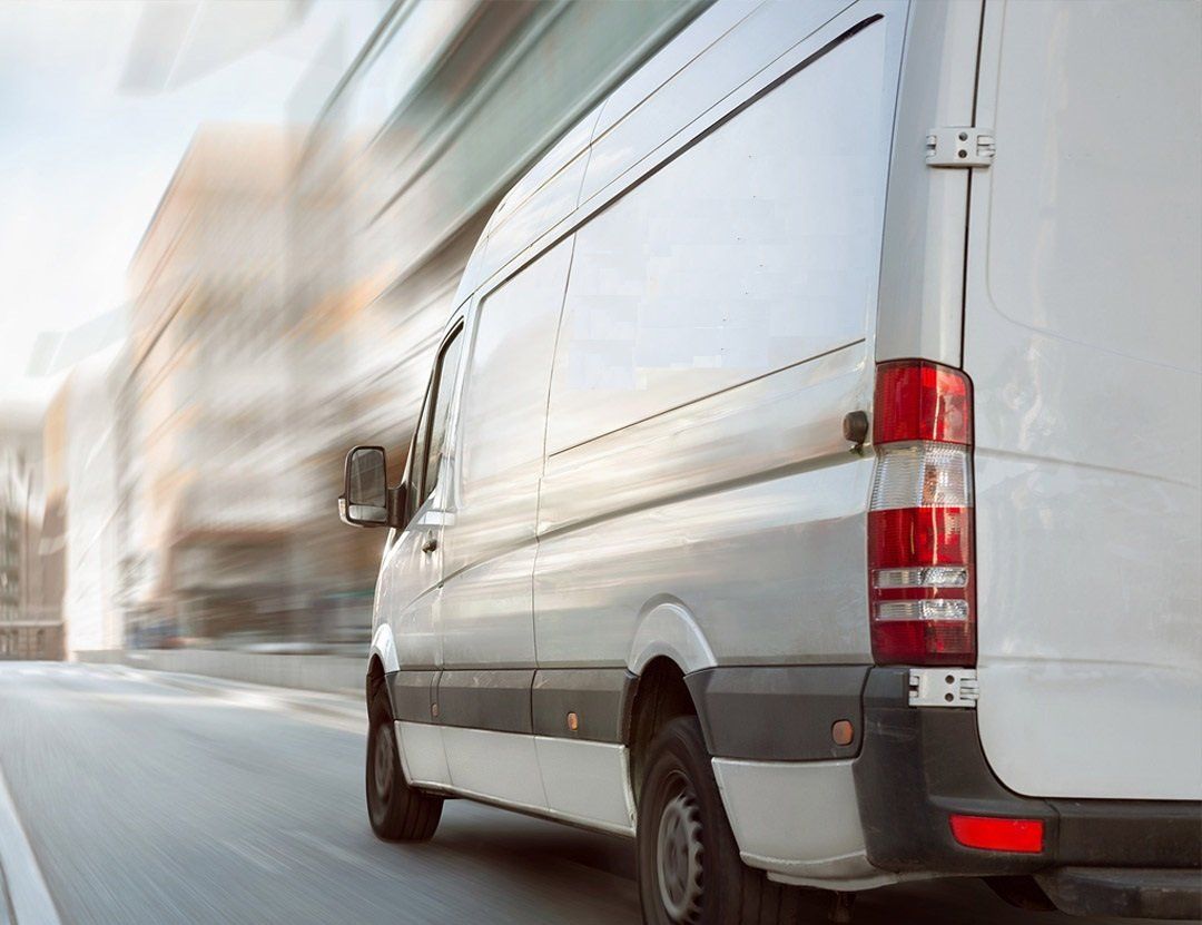 A white van is driving down a city street.