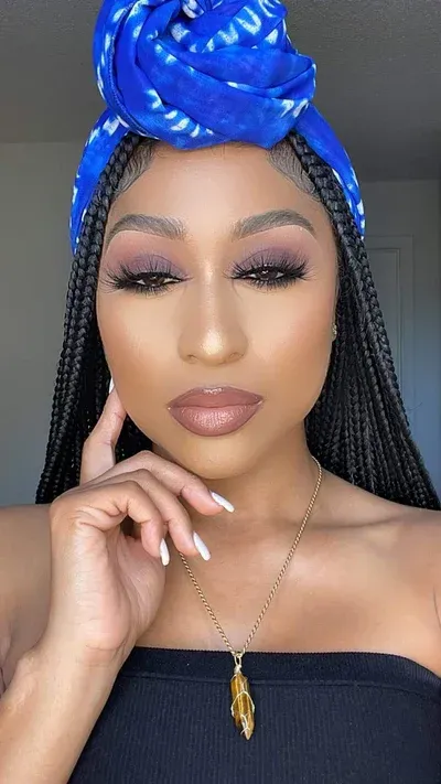 A woman with braids is wearing a blue headband and a necklace.