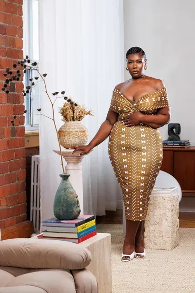 A woman in a gold dress is standing in a living room.