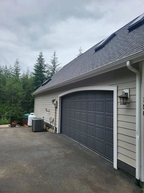 Freshly painted garage exterior with gray siding and black overhead door