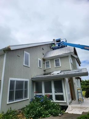 Exterior painting in progress on a two-story home using professional lift equipment