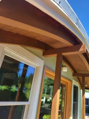 Custom wood entry with freshly stained beams, soffit, and trim