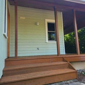 Stained wood front porch with freshly finished deck and steps