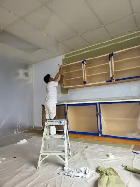 Kitchen cabinet refinishing preparation with doors removed and surfaces masked for painting
