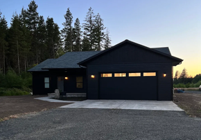 Black custom home with freshly painted exterior and garage doors